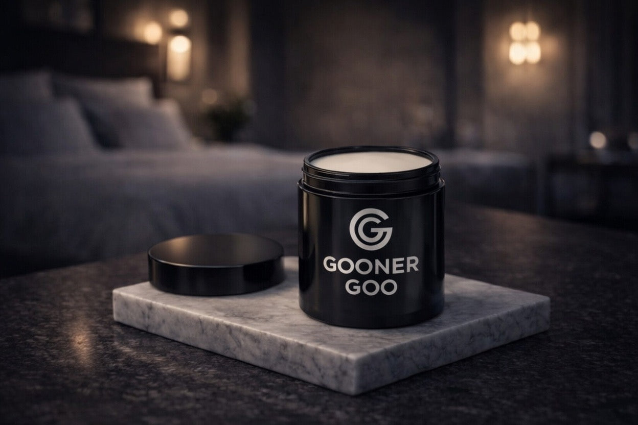 Black container labeled 'GOONER GOO' on a marble coaster with a blurred bedroom background